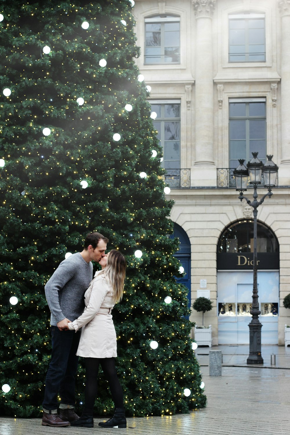 man and woman kissing beside of Christmas tree