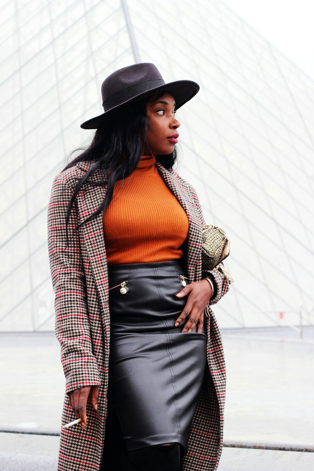 woman wearing orange sweater and black leather skirt with beige trench caot  standing on street looking at side photo – Free Clothing Image on Unsplash