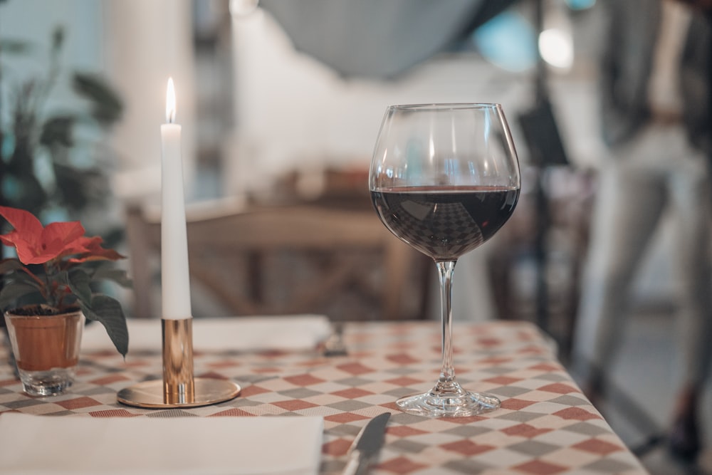 white candle stick beside of goblet glass