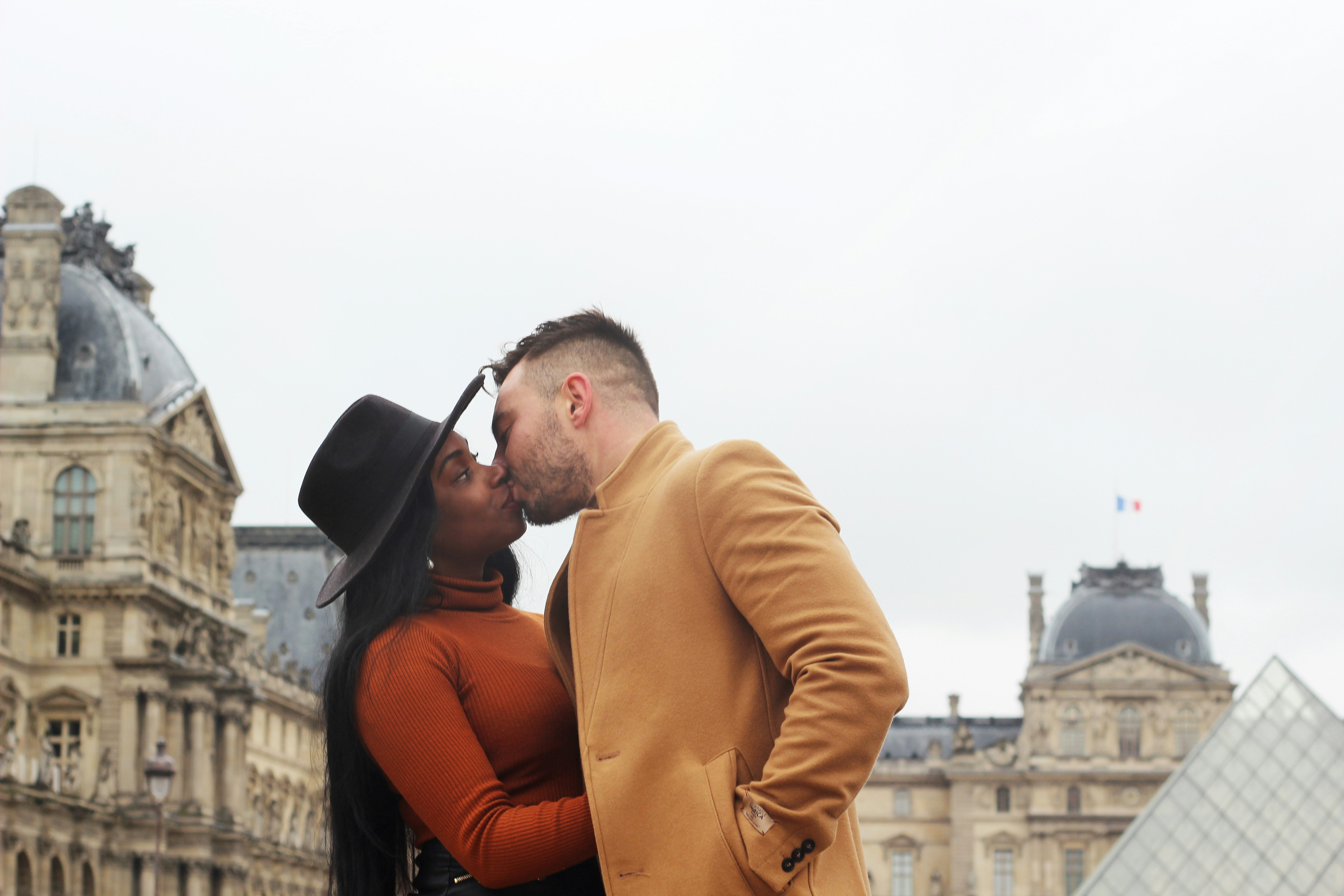 man kissing a woman wearing orange sweater