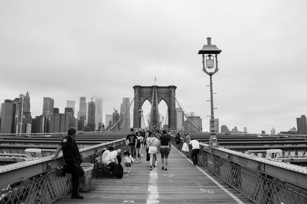 grayscale photography of people walking on bridge