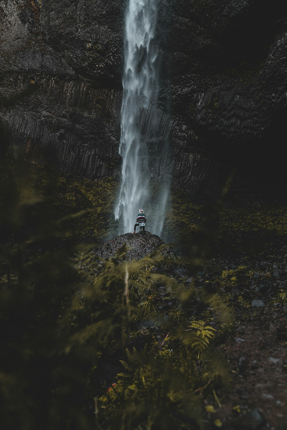 Photographie d’une personne debout faisant face à des chutes d’eau pendant la journée