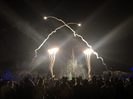 Una familia feliz disfrutando de un parque temático de Disney con castillos y fuegos artificiales al atardecer.