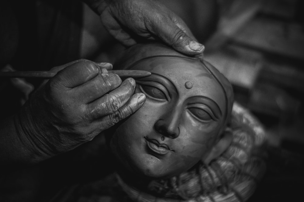 uma foto em preto e branco de uma pessoa fazendo uma máscara