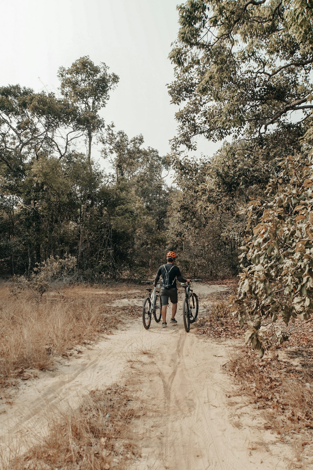 man walking while holding on to two bicycles