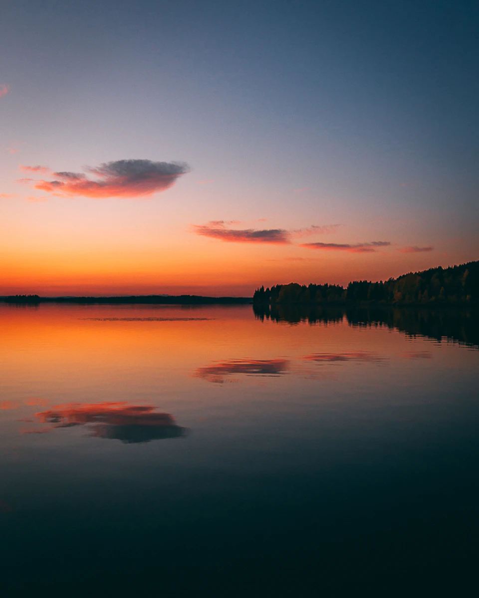 Serene lake at sunset with vibrant orange and pink hues reflecting on calm water