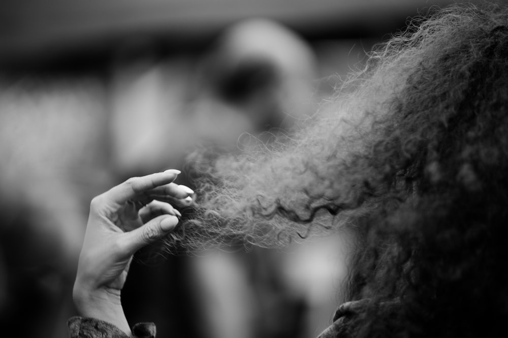 fotografia em escala de cinza da mulher que segura o cabelo encaracolado longo