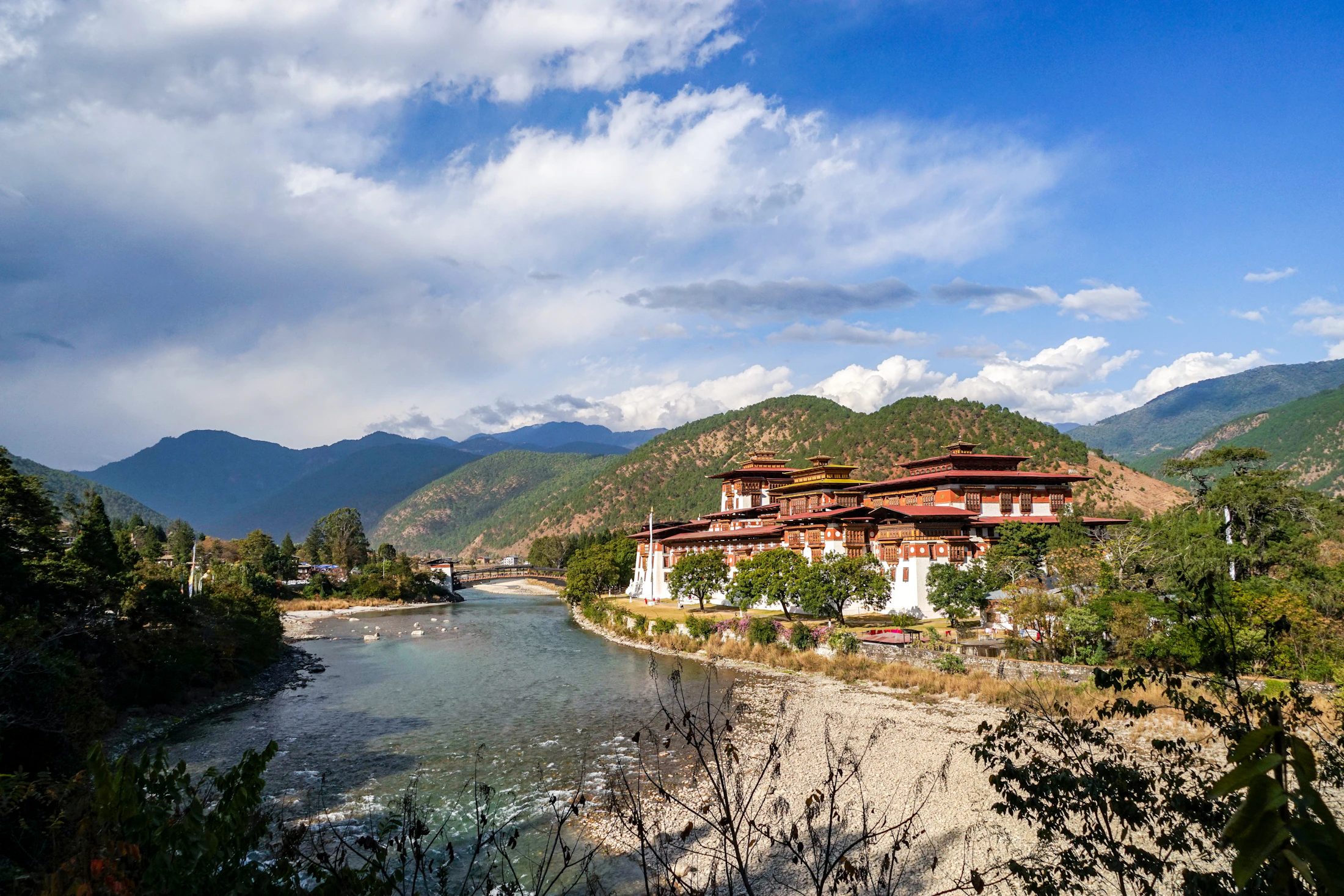 Punakha Dzong at the meeting of two rivers under big white clouds