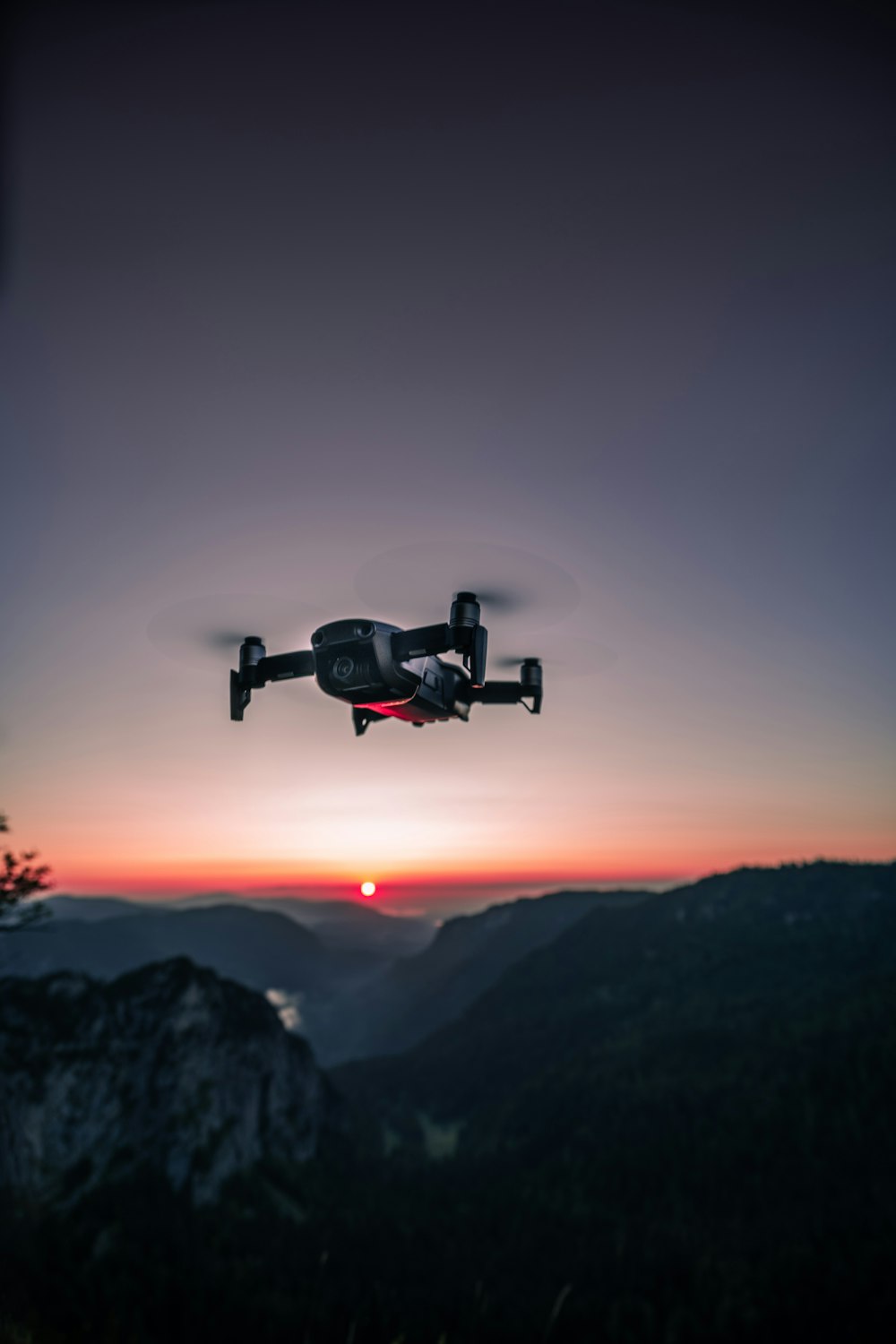 Ver fotografía del dron cuadricóptero negro en el aire durante el amanecer