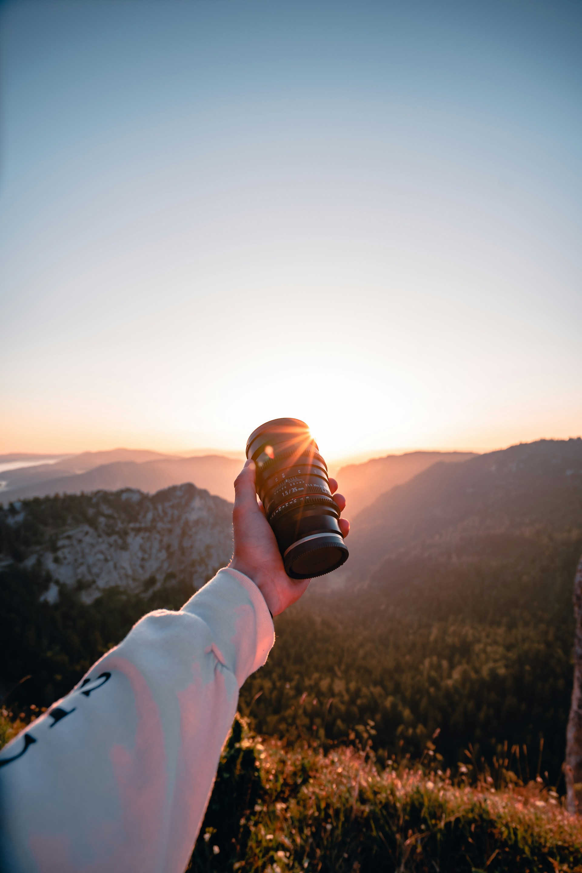 A vibrant close-up of a camera lens capturing a stunning mountain landscape at sunrise.