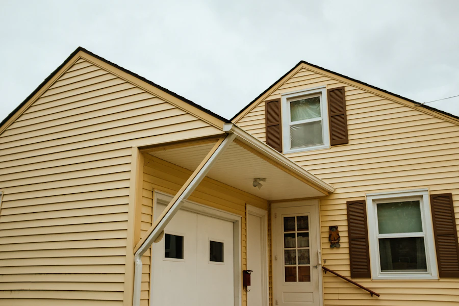 Two-story suburban home freshly clad in light vinyl siding under a clear sky