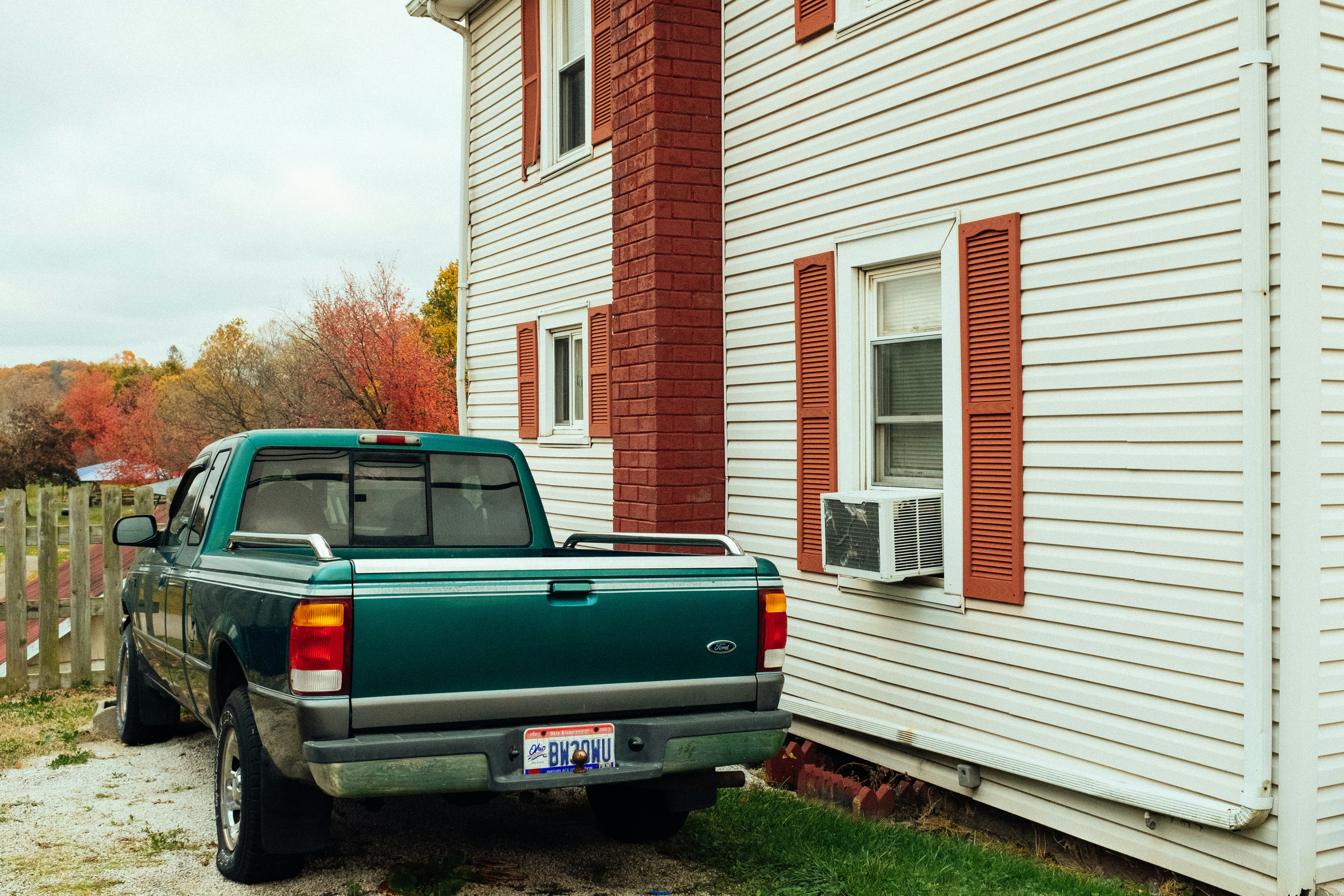 green crew cab pickup truck beside house