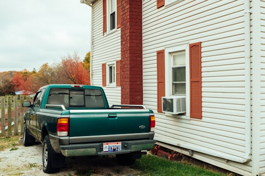 Technician installing a heat pump outside a cozy Quebec home on a crisp autumn day.