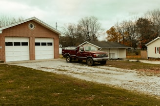 red pickup truck parking in front of garage