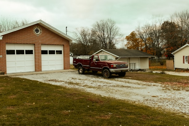 red pickup truck parking in front of garage