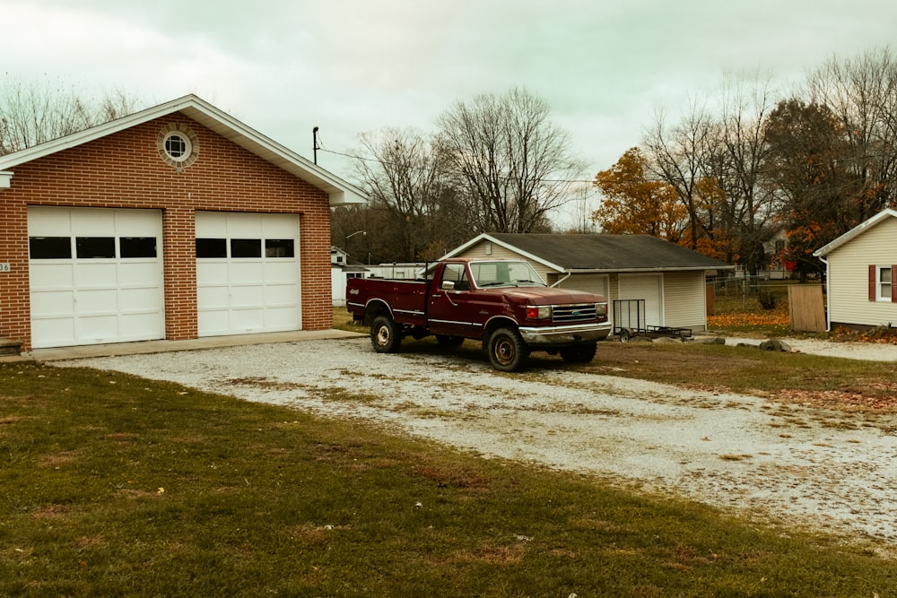 red pickup truck parking in front of garage