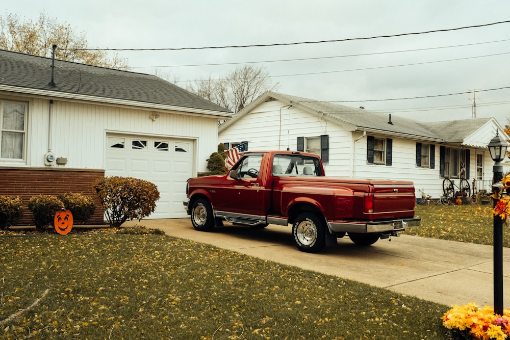 red single-cab pickup truck parking in front of garage during daytime