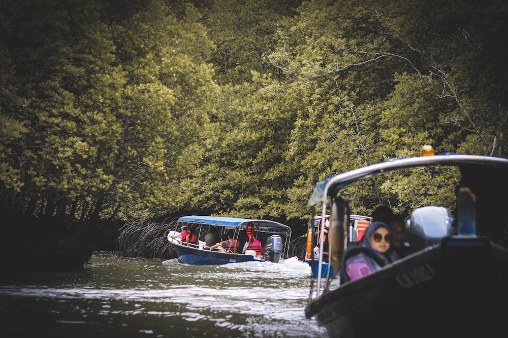people in blue boat on river surrounded with green trees