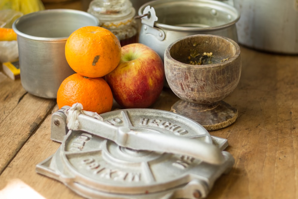 stack of orange and apples by pots on table top