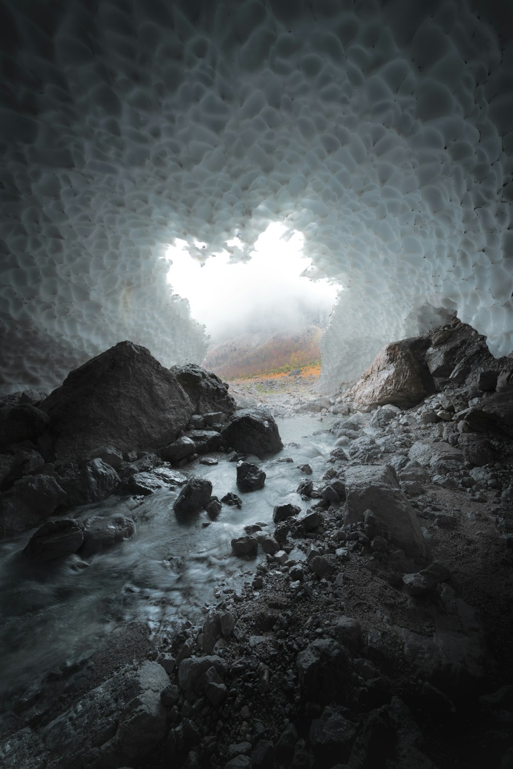 a cave filled with rocks and water under a cloudy sky