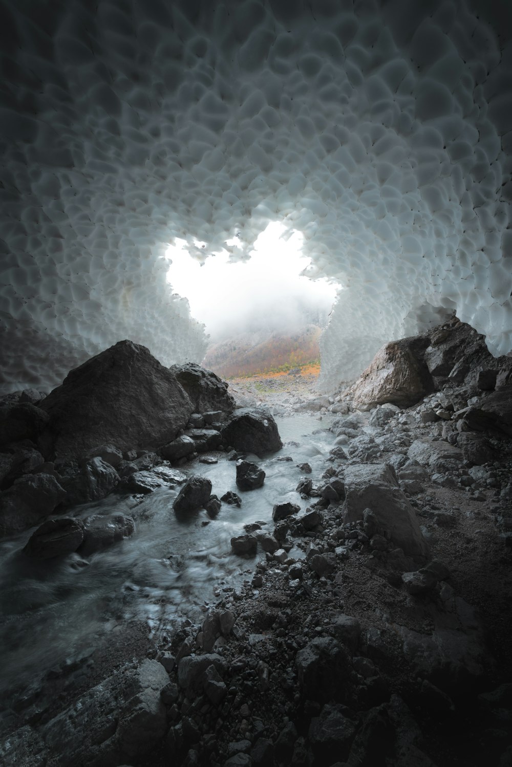 uma caverna cheia de rochas e água sob um céu nublado