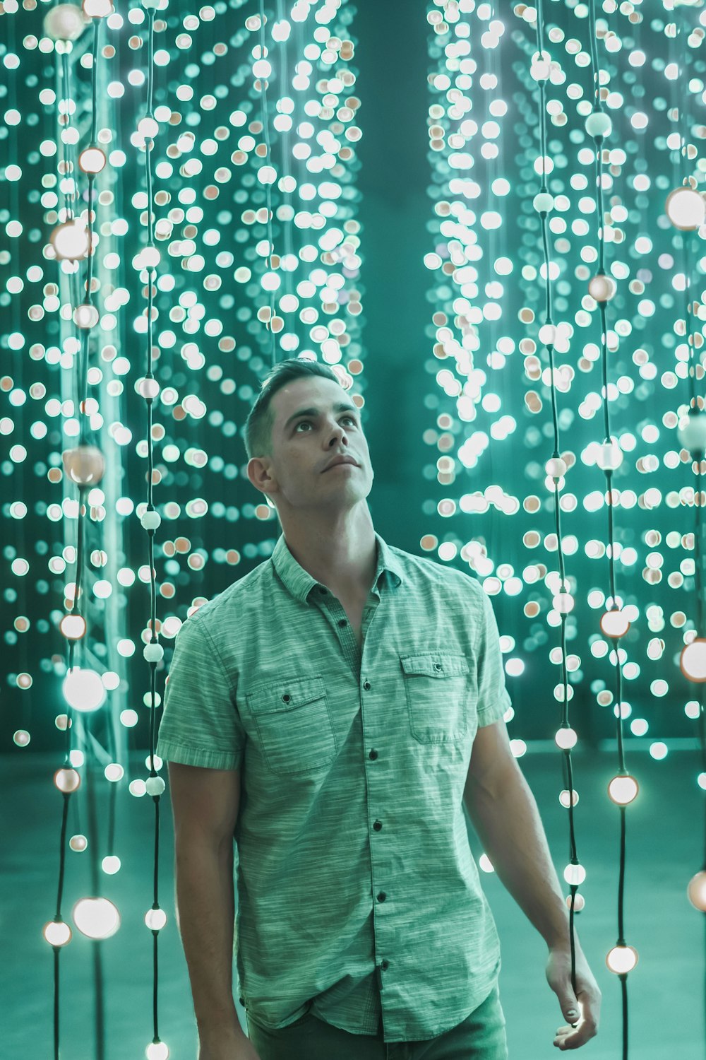 man standing below turned-on hanging string lights