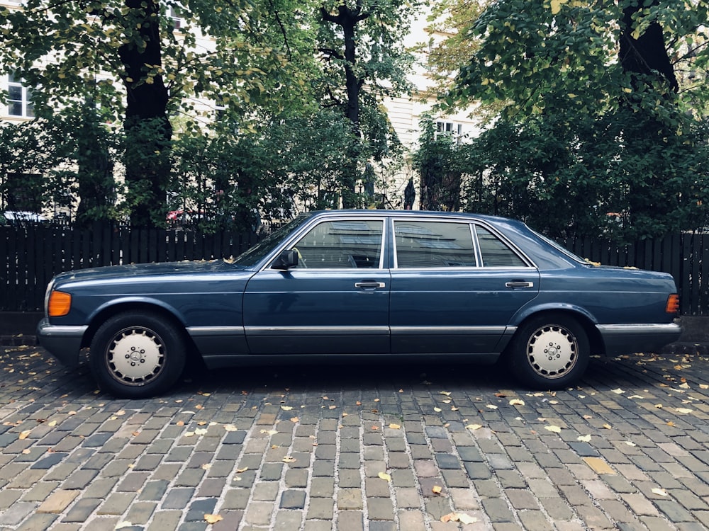 gray sedan parking near fence beside trees