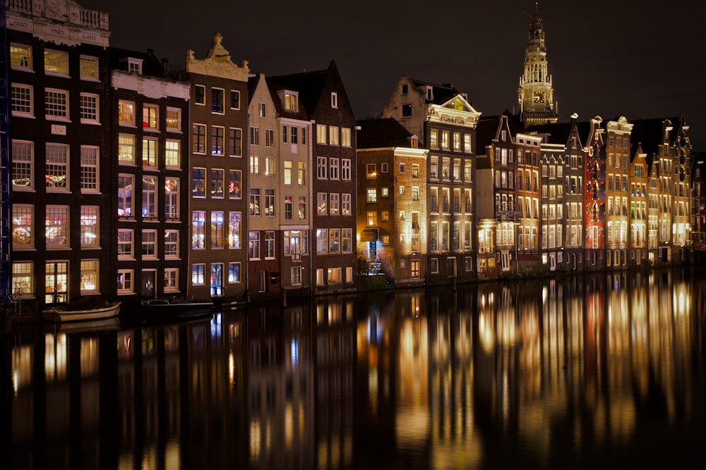 view photography of lighted buildings near sea during nighttime