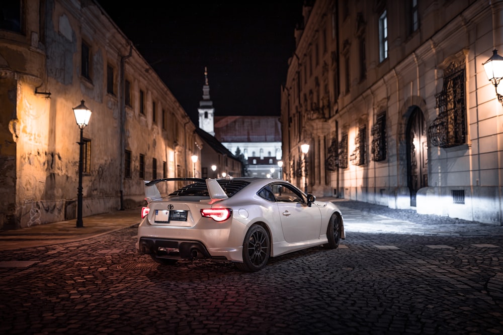 a white sports car parked on a cobblestone street