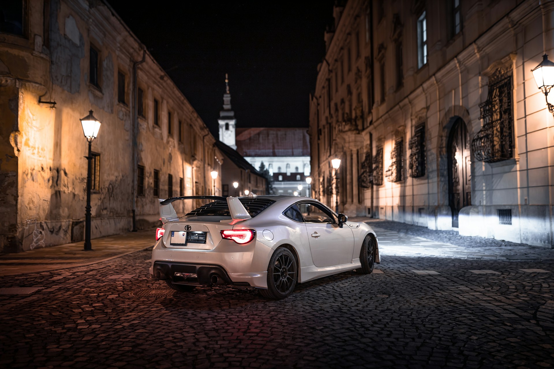 a white sports car parked on a cobblestone street