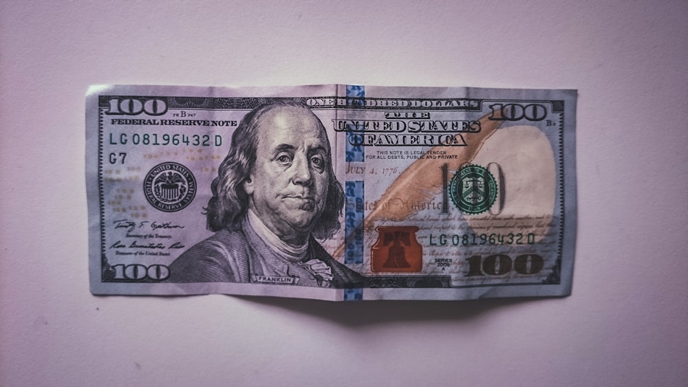 Un billete de cien dólares doblado en un pedazo de papel
