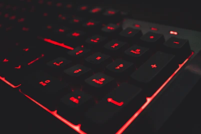 A sleek dark-themed gaming keyboard with glowing RGB lights illuminating the keys.