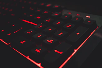 A sleek dark-themed gaming keyboard with glowing RGB lights illuminating the keys.