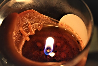 Close-up of a lit candle with a flickering flame and soft wax texture