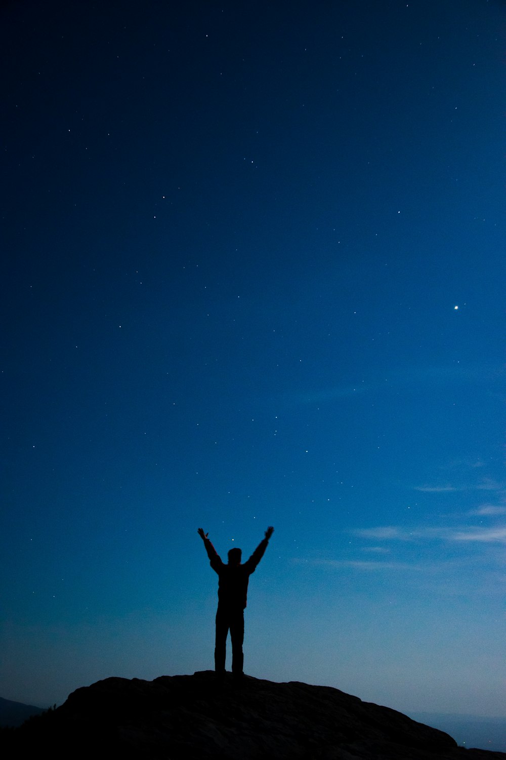 silhouette d’homme debout sur la colline avec les bras grands ouverts