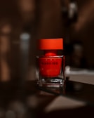 Artistic shot of a perfume bottle with deep shadows and red accent lighting.