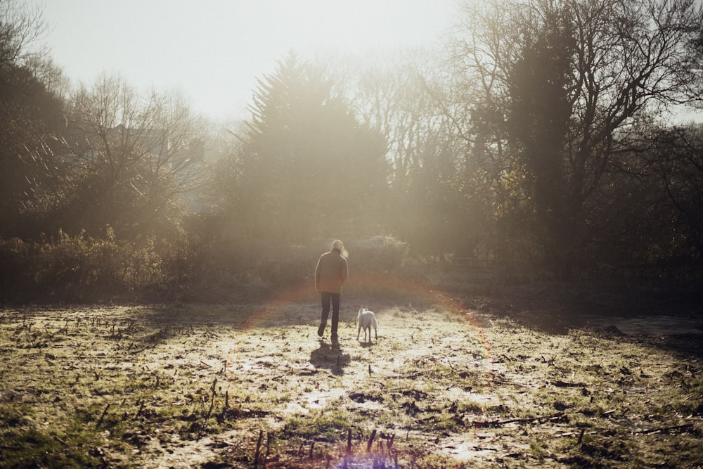 woman and animal on grass field near trees during day