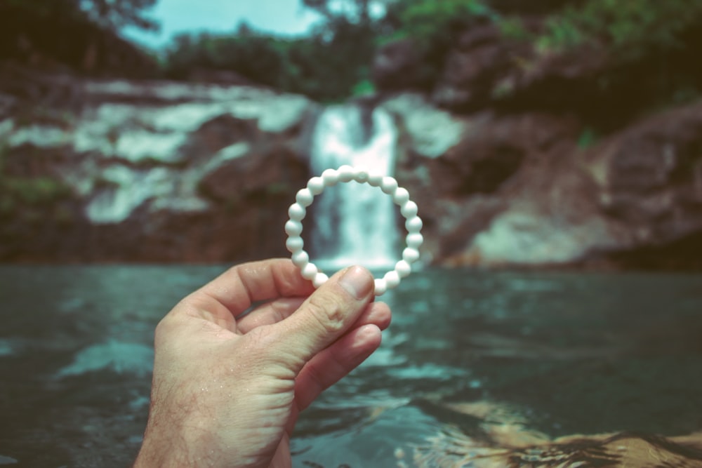 person holding white beaded bracelet