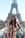 A smiling woman enjoying a café terrace in Paris with the Eiffel Tower in the background.