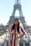 Smiling woman standing in front of the Eiffel Tower on a sunny day.
