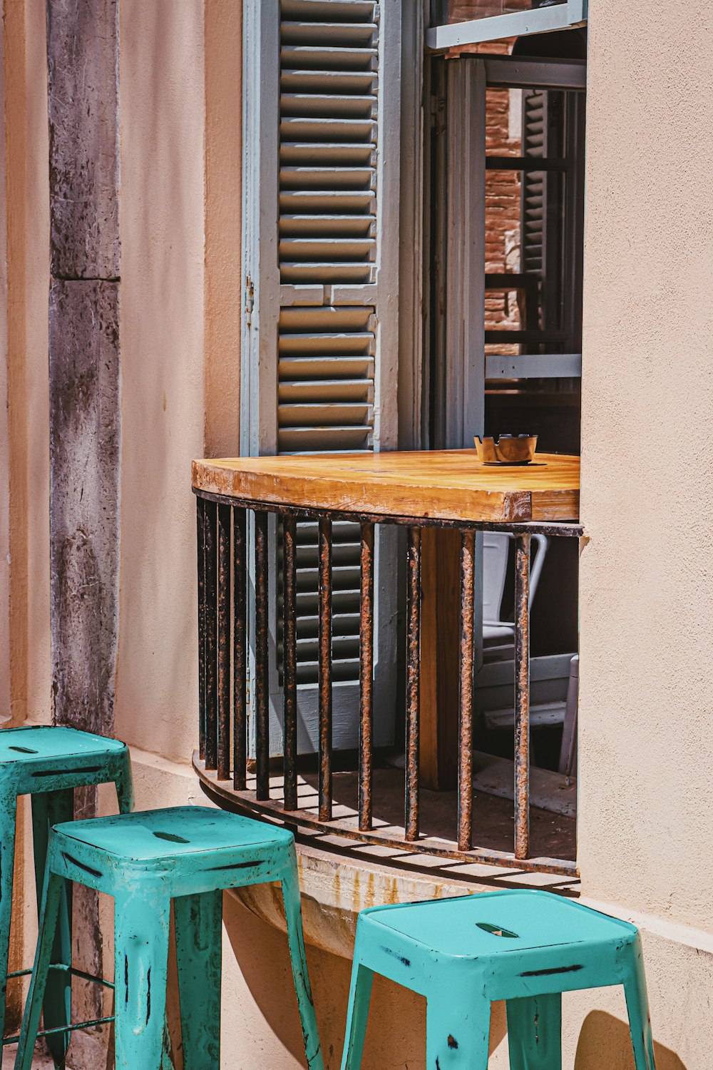 three green metal stools near window