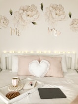 white heart cushion pillow near coffee in mug, white book, and cookies on tray on top of white bed
