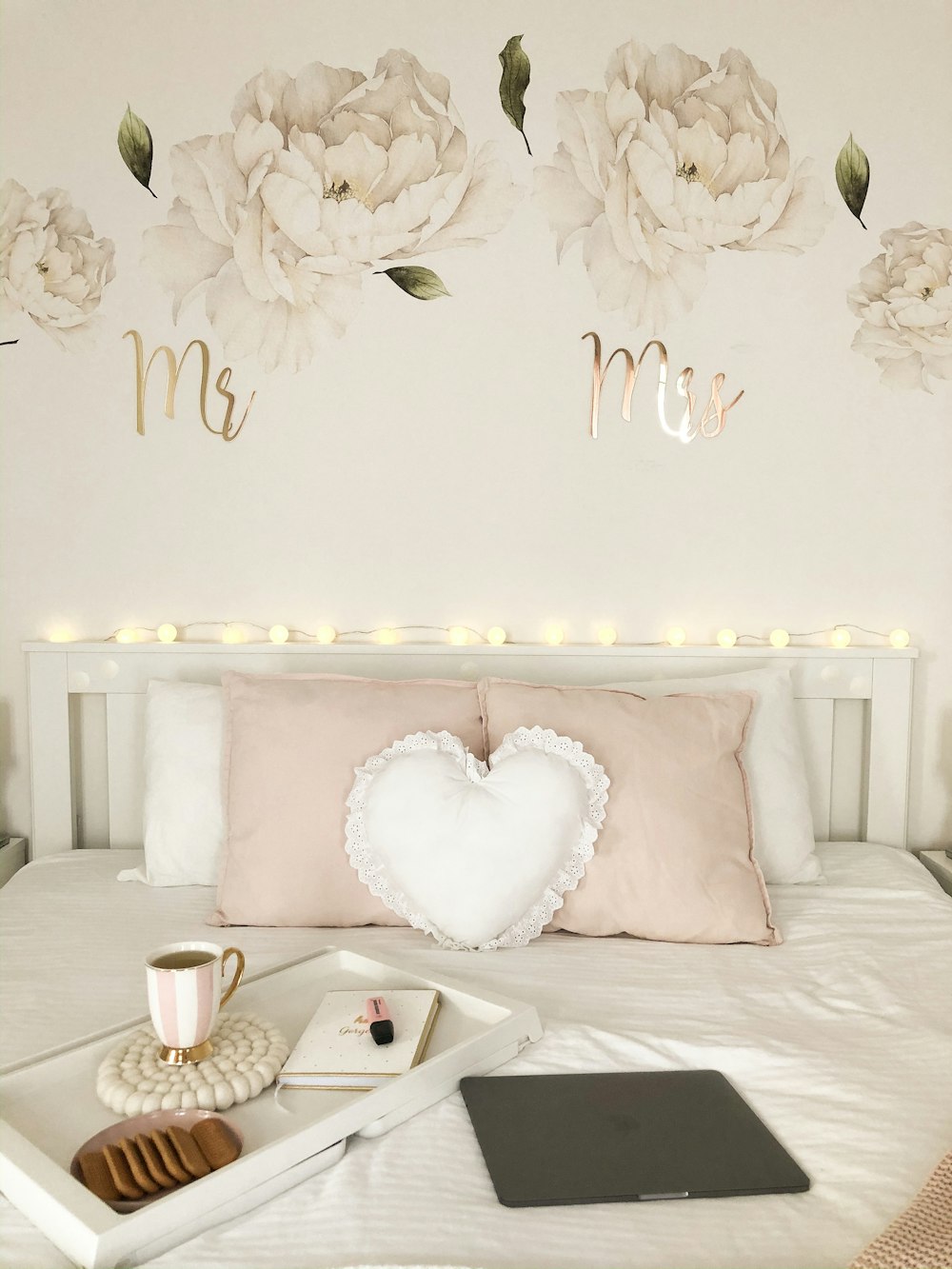 white heart cushion pillow near coffee in mug, white book, and cookies on tray on top of white bed