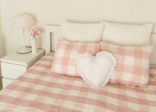 pink and white plaid pillows on bedsheet