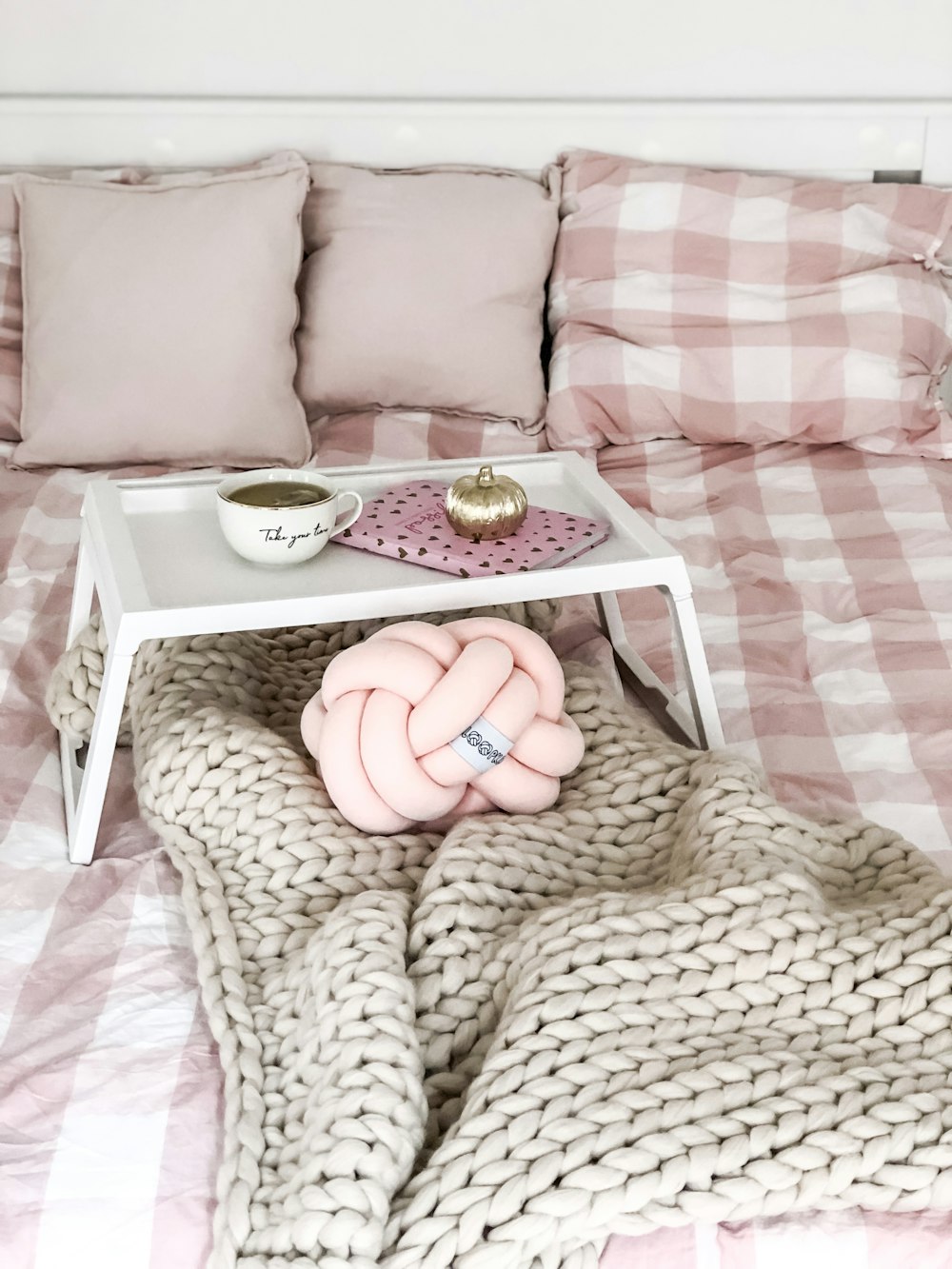 a bed with a pink blanket and a white tray with a ring on it