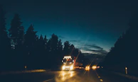Nighttime shot of a Wicho Transport LLC truck on the highway, headlights cutting through the dark.