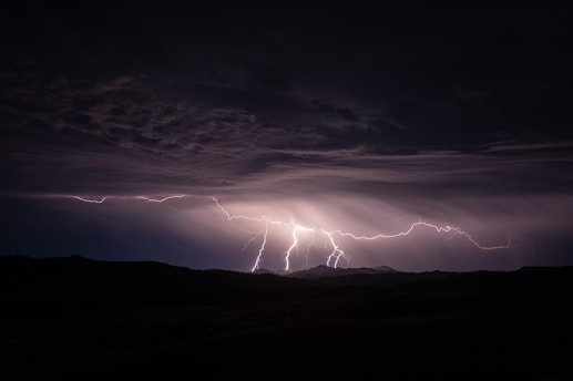 silhouette photography of mountain and lightning bolt