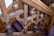 Intricately carved wooden banister with ornate detailing on a stairway, featuring spherical and cylindrical designs. The wood has an aged, polished appearance with visible grain patterns.