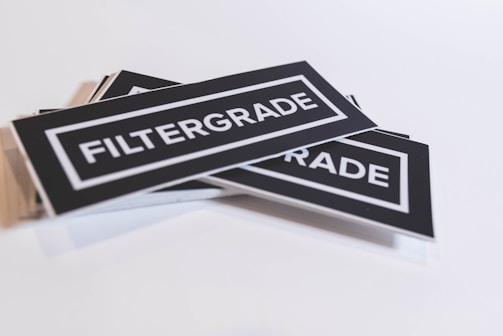 A stack of rectangular black stickers with the word 'FILTERGRADE' printed in bold white letters at the center. The stickers are placed at an angle against a plain white background.