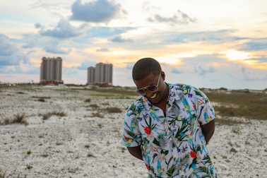 smiling man wearing floral dress shirt standing on the grass field
